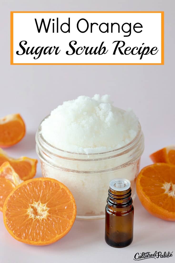Wild Orange Sugar Scrub Recipe shown in glass jar with oranges around it.