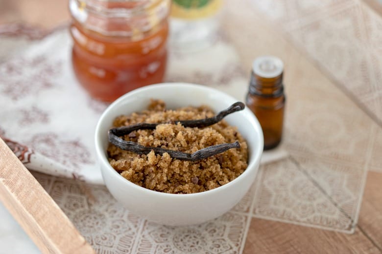 Brown Sugar Body Scrub shown in white bowl with honey and essential oil.