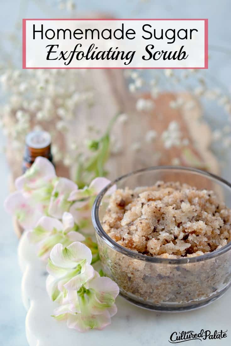 Homemade Sugar Exfoliating Scrub shown in glass jar with flowers, cutting board in background and text overlay.