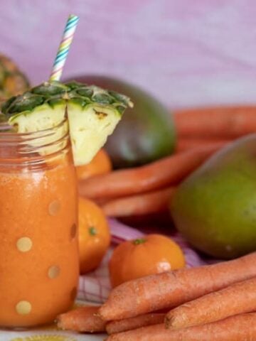 Carrot Juice Recipe for Kids shown in glass jar with straw and fruit around