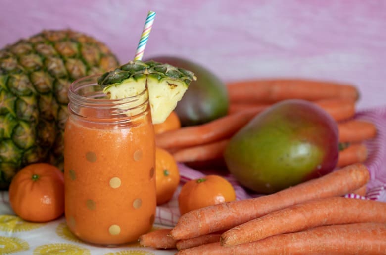 Carrot Juice Recipe for Kids shown in glass jar with straw and fruit around