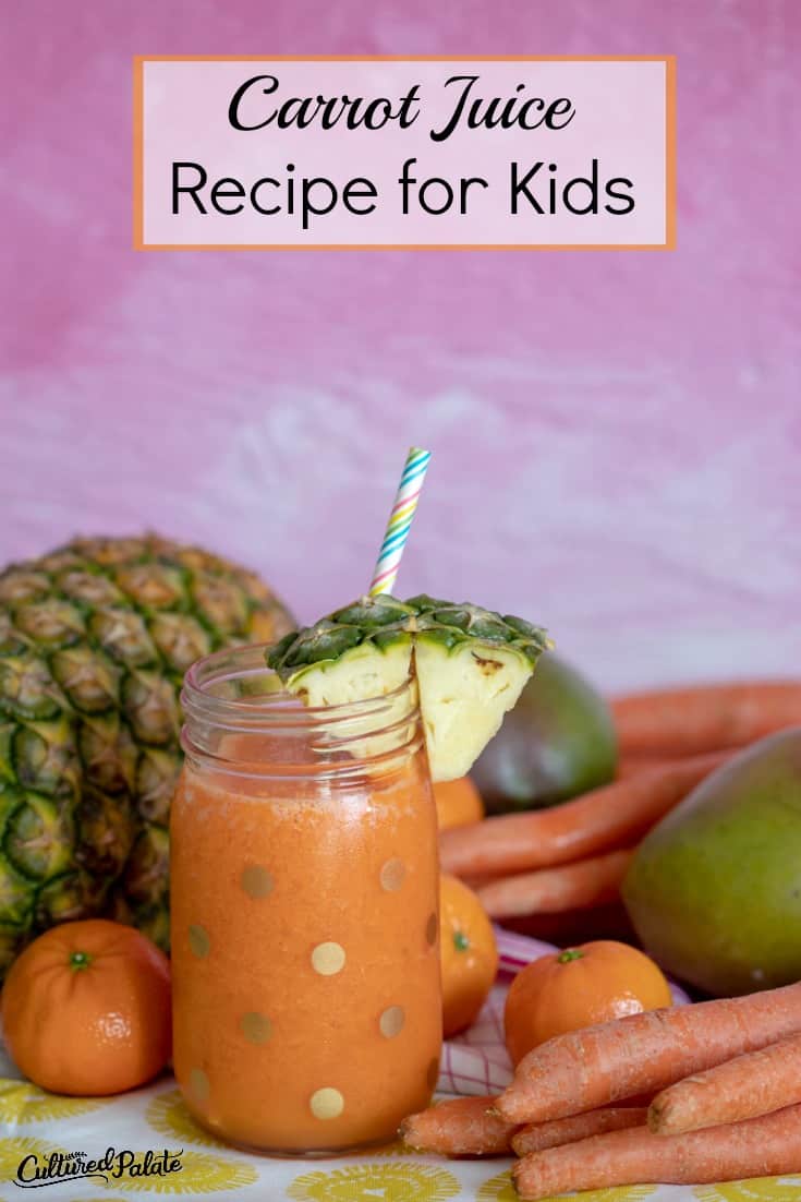 Carrot Juice Recipe for Kids shown from a distance with pink backround and fruits and veggies around.