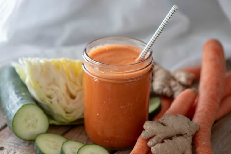 Carrot Juice Recipe for Weight Loss shown with white background and veggies around jar.