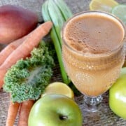 Green Carrot Juice Recipe shown with fruits and veggies around glass.