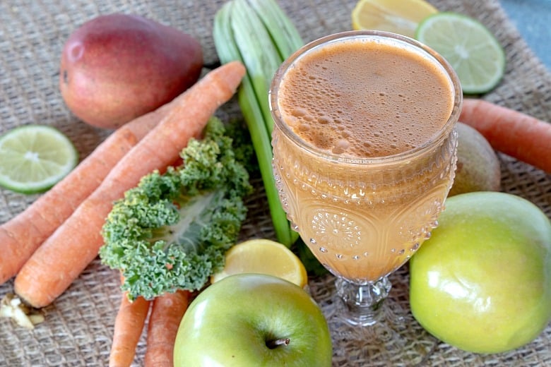 Green Carrot Juice Recipe shown with fruits and veggies around glass.