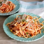 Crockpot Chicken Spaghetti Recipe shown on green plates with fork to the side.