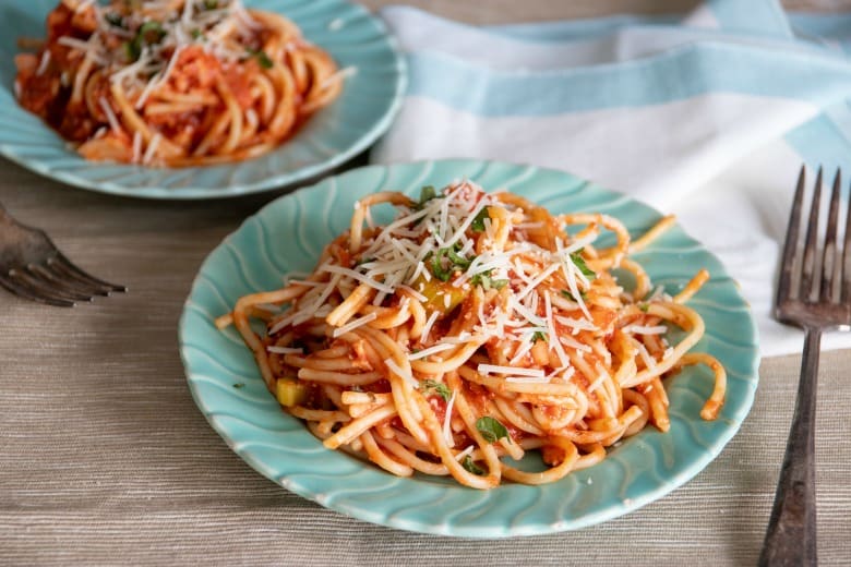 Crockpot Chicken Spaghetti Recipe shown on green plates with fork to the side.