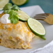 A piece of Crockpot White Chicken Enchilada Casserole on a white plate with fork to the side.