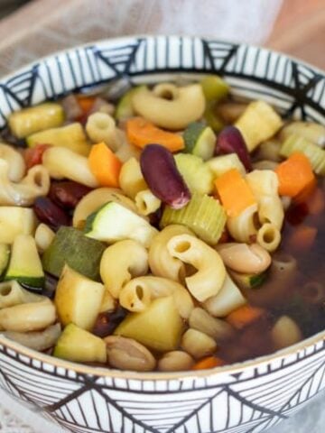 Minestrone Soup in the Crockpot shown in a black and white bowl on wooden tray.