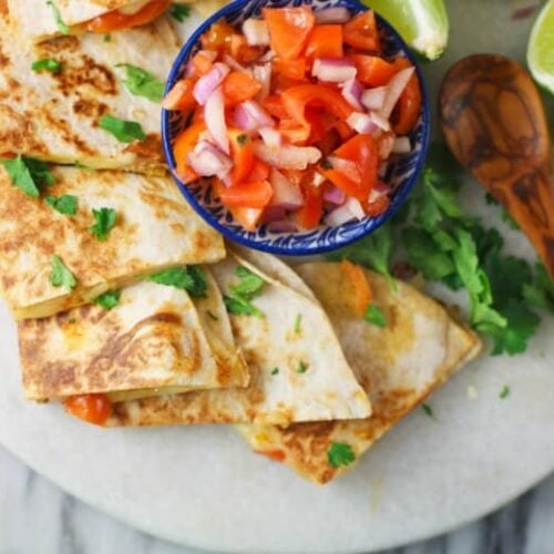 Mozzarella Quesadillas shown from overhead on white platter and salsa in the center.