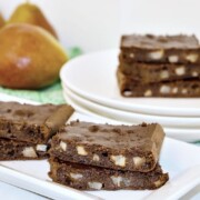 Pear brownies shown on a platter with pears in the background.