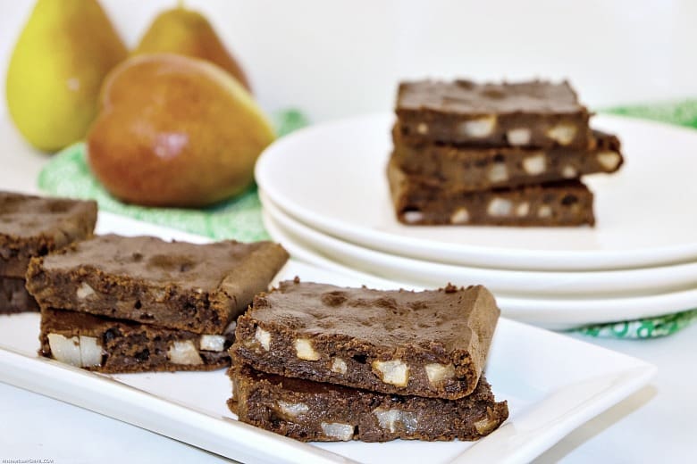 Pear brownies shown on a platter with pears in the background.