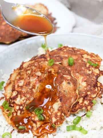 Egg Foo Young pancakes over rice in a bowl with gravy on top