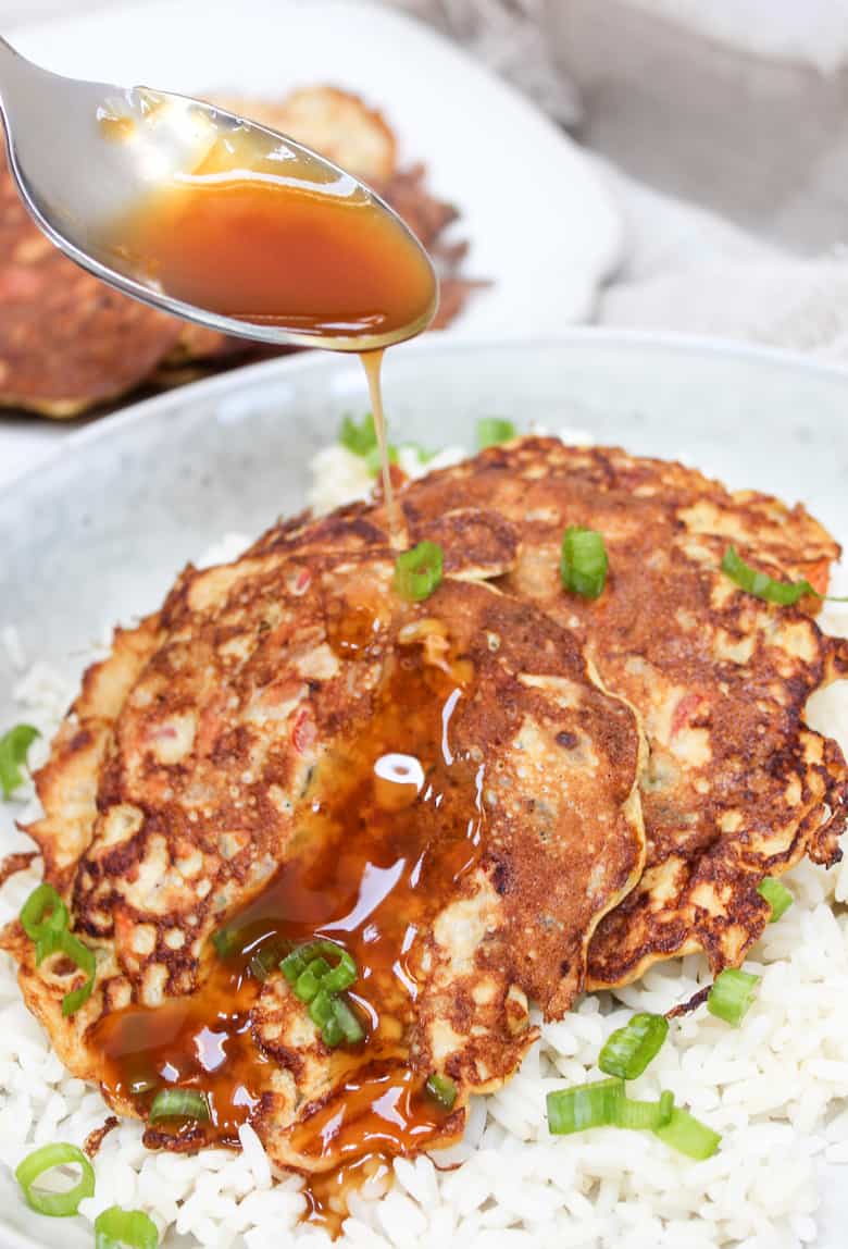 Egg Foo Yound pancakes over rice in a bowl with gravy on top