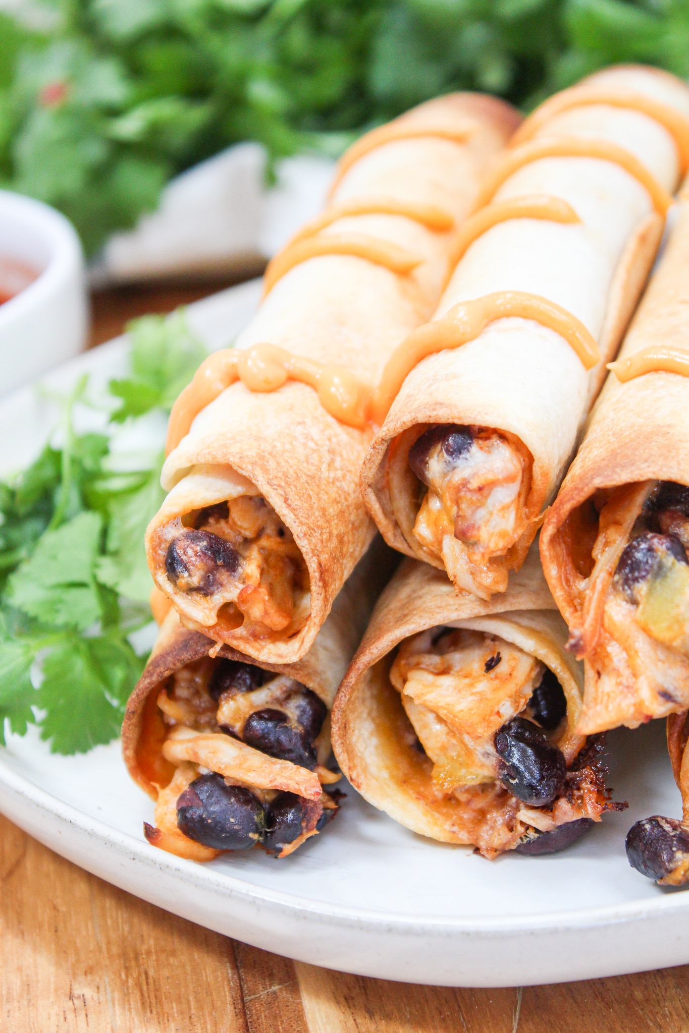 Oven Baked Chipotle Chicken Taquitos stacked on a white plate